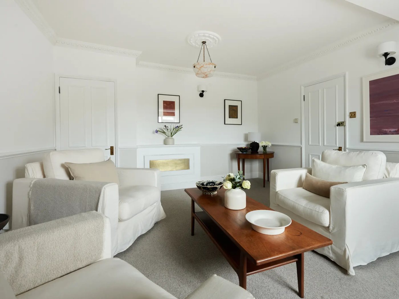 Room 1 — armchairs and a walnut coffee table beneath the pendant light